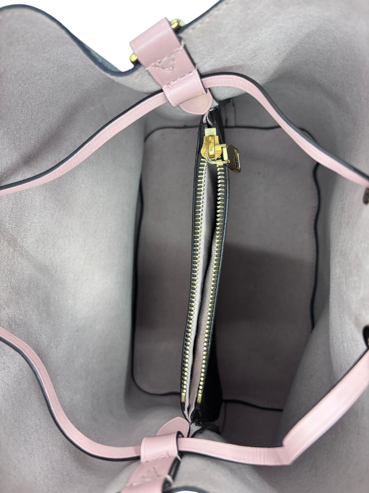 Interior view of Posh Purse Co Louis Vuitton Neonoe MM bucket bag featuring a pink lining and central zip pocket