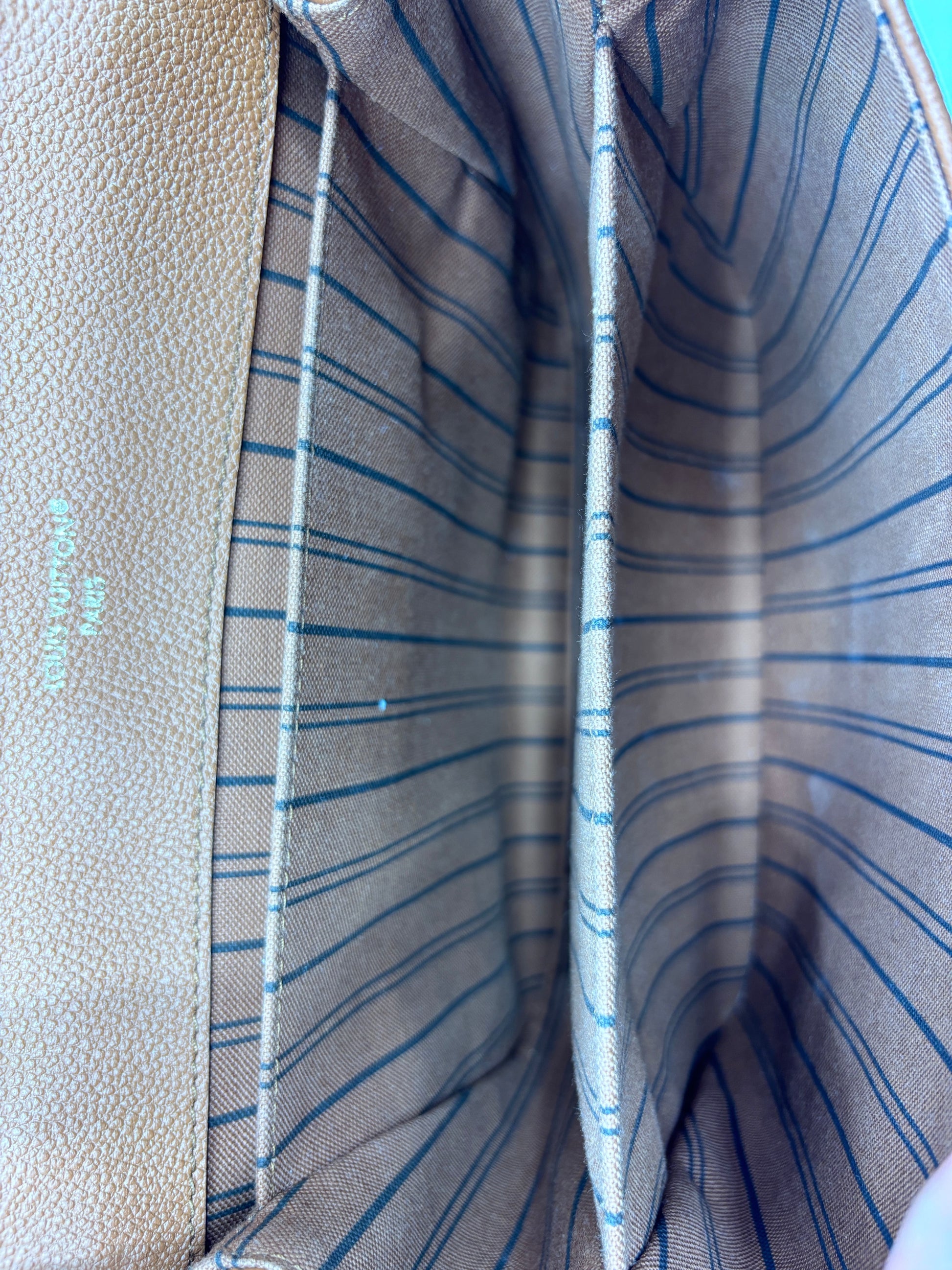 Interior of Posh Purse Co. Louis Vuitton Pochette Metis handbag showing brown striped fabric lining and leather trim