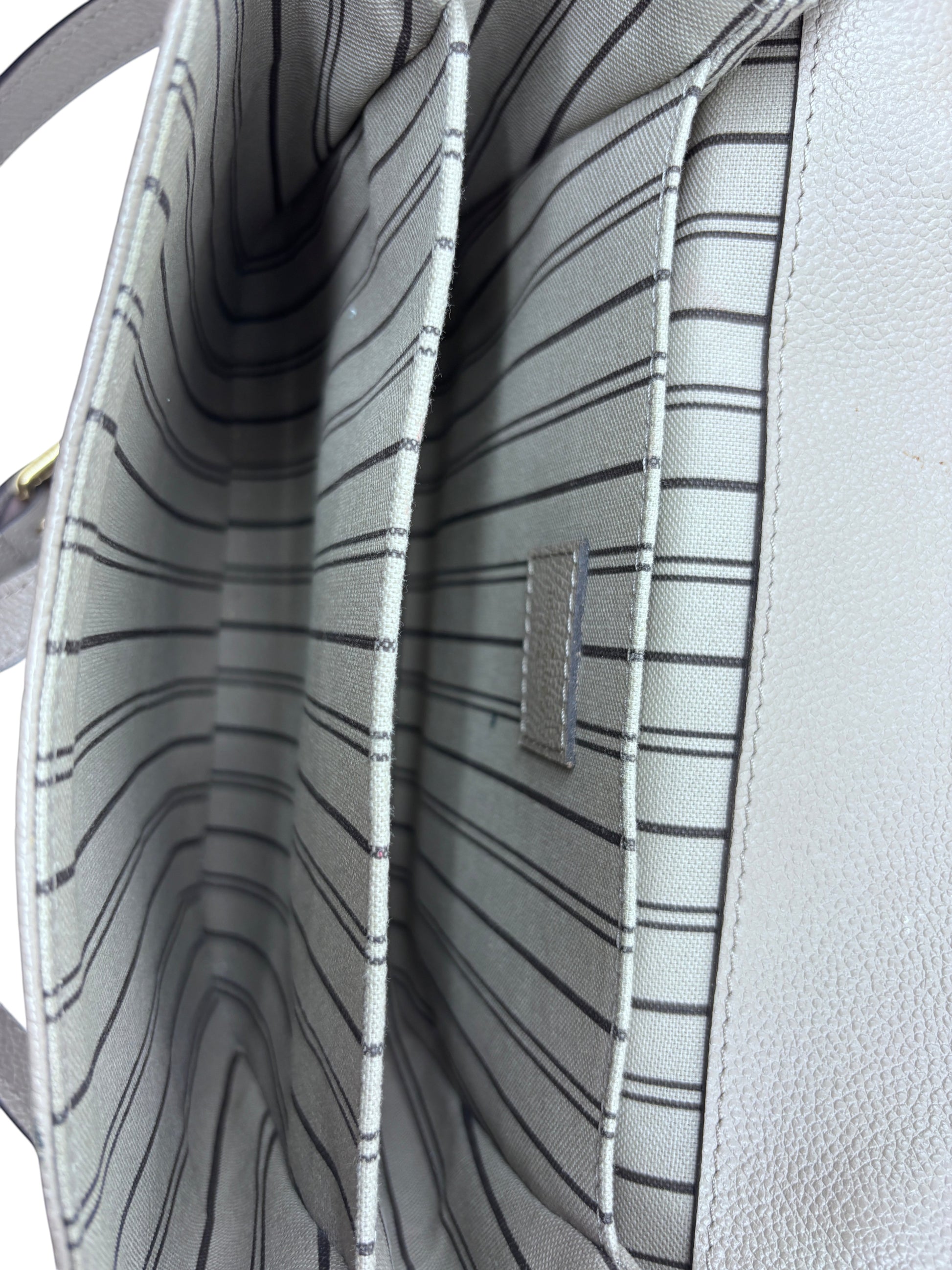 Interior of Posh Purse Co Louis Vuitton Pochette Metis bag featuring three compartments with striped fabric lining