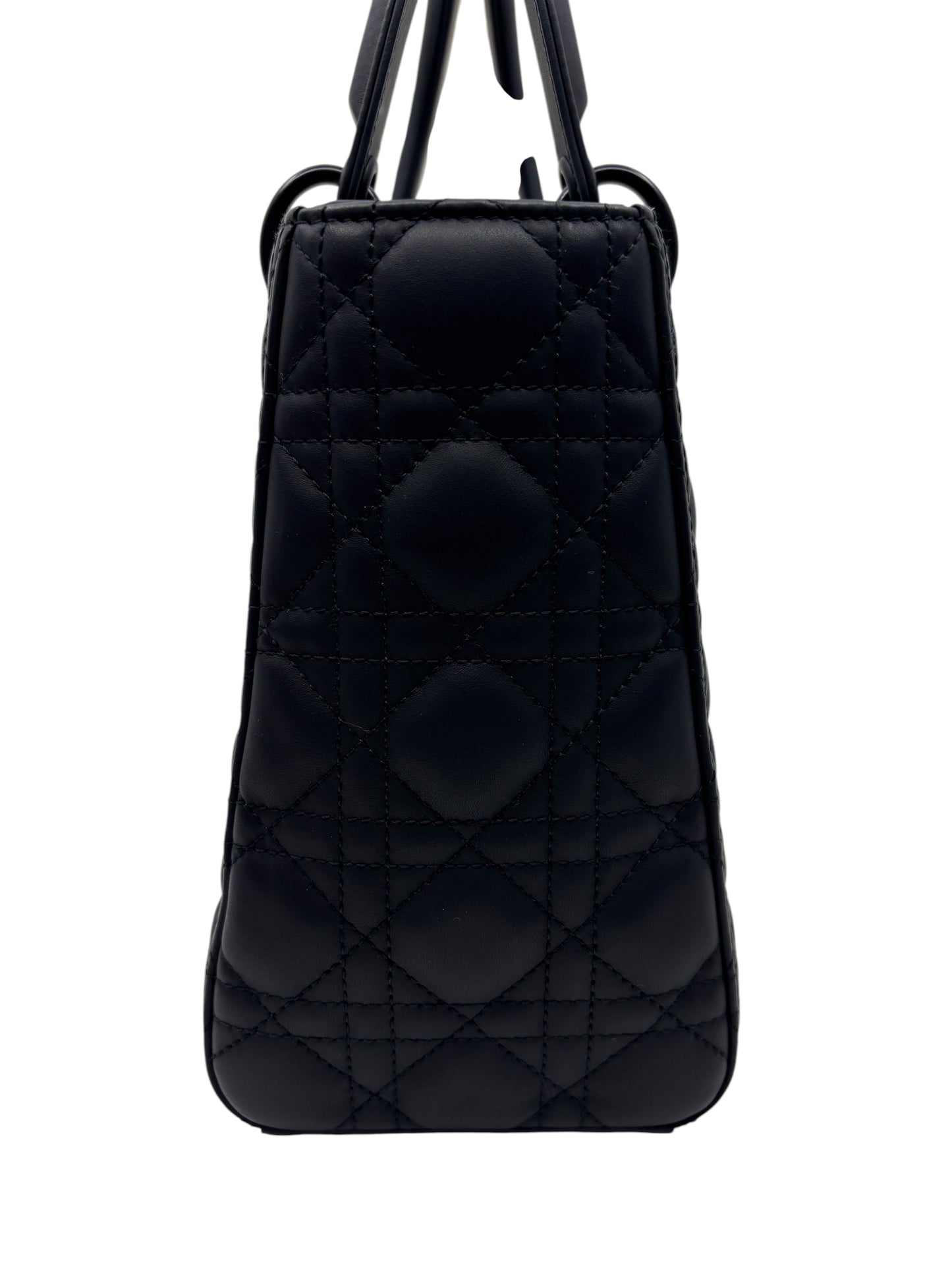 Posh Purse Co. medium Lady Dior bag in matte black leather with signature cannage quilting, side profile view.