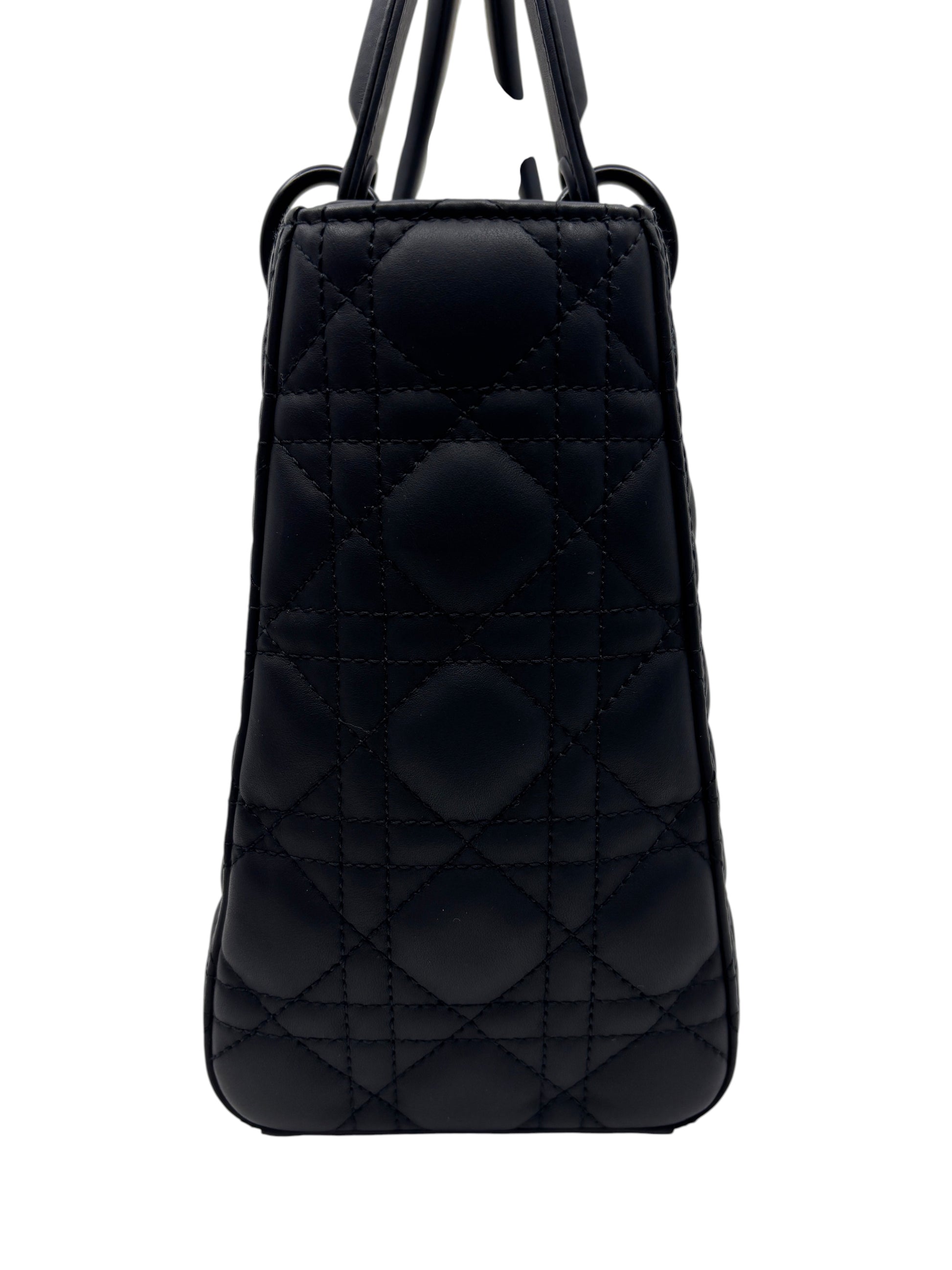 Posh Purse Co. medium Lady Dior bag in matte black leather with signature cannage quilting, side profile view.
