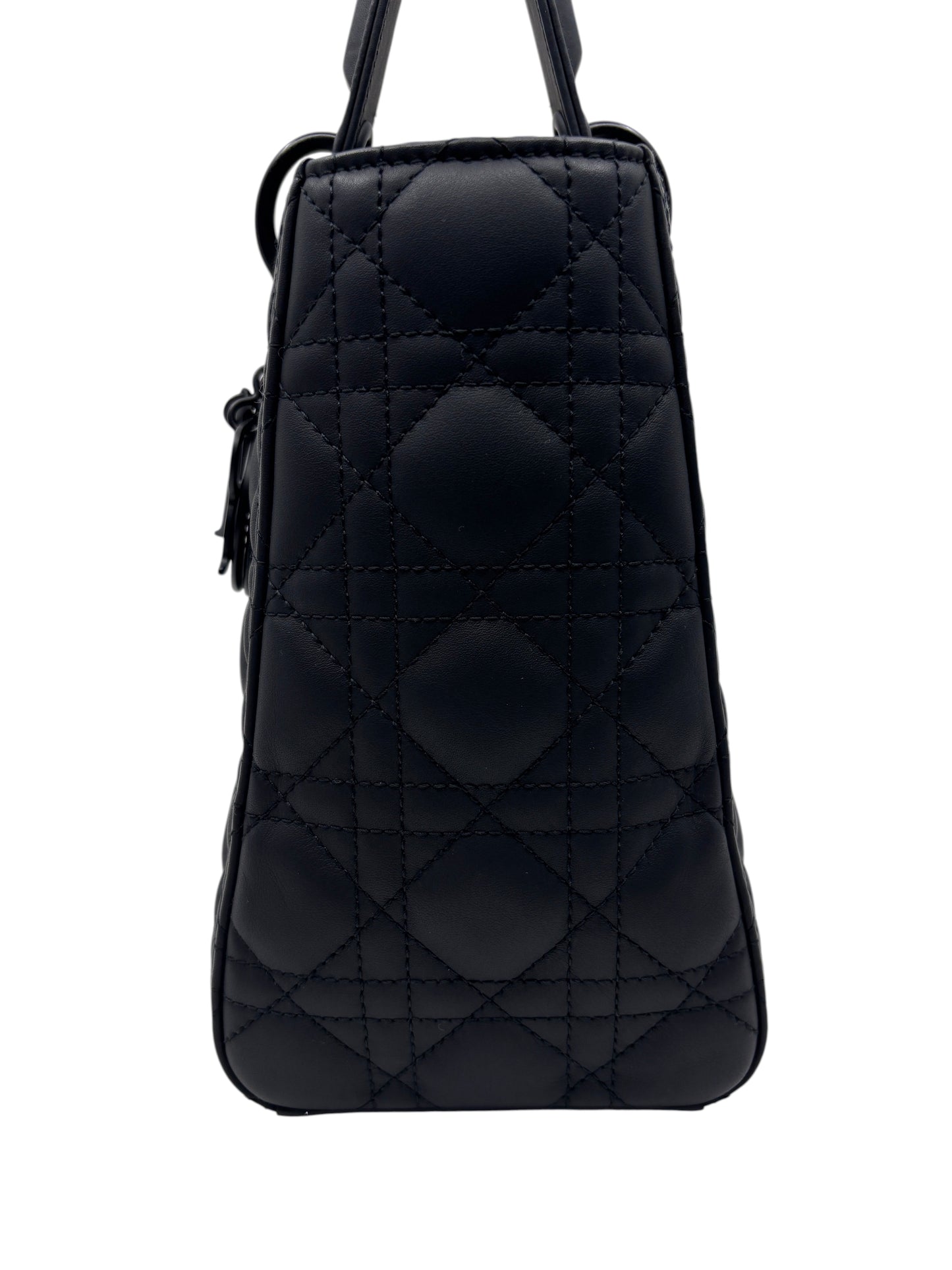 Side view of a Posh Purse Co. medium Lady Dior bag in matte black leather with signature cannage quilting.