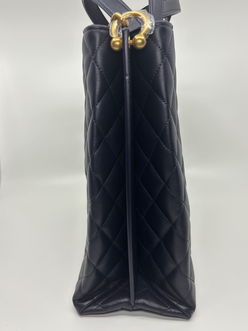 Posh Purse Co. navy blue quilted leather Chanel tote bag with gold hardware and protective stickers.