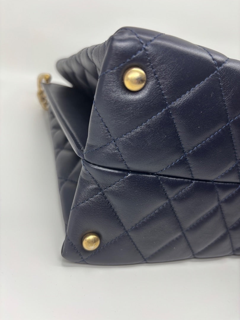 Posh Purse Co. navy blue quilted leather Chanel tote bag with gold hardware and protective stickers.