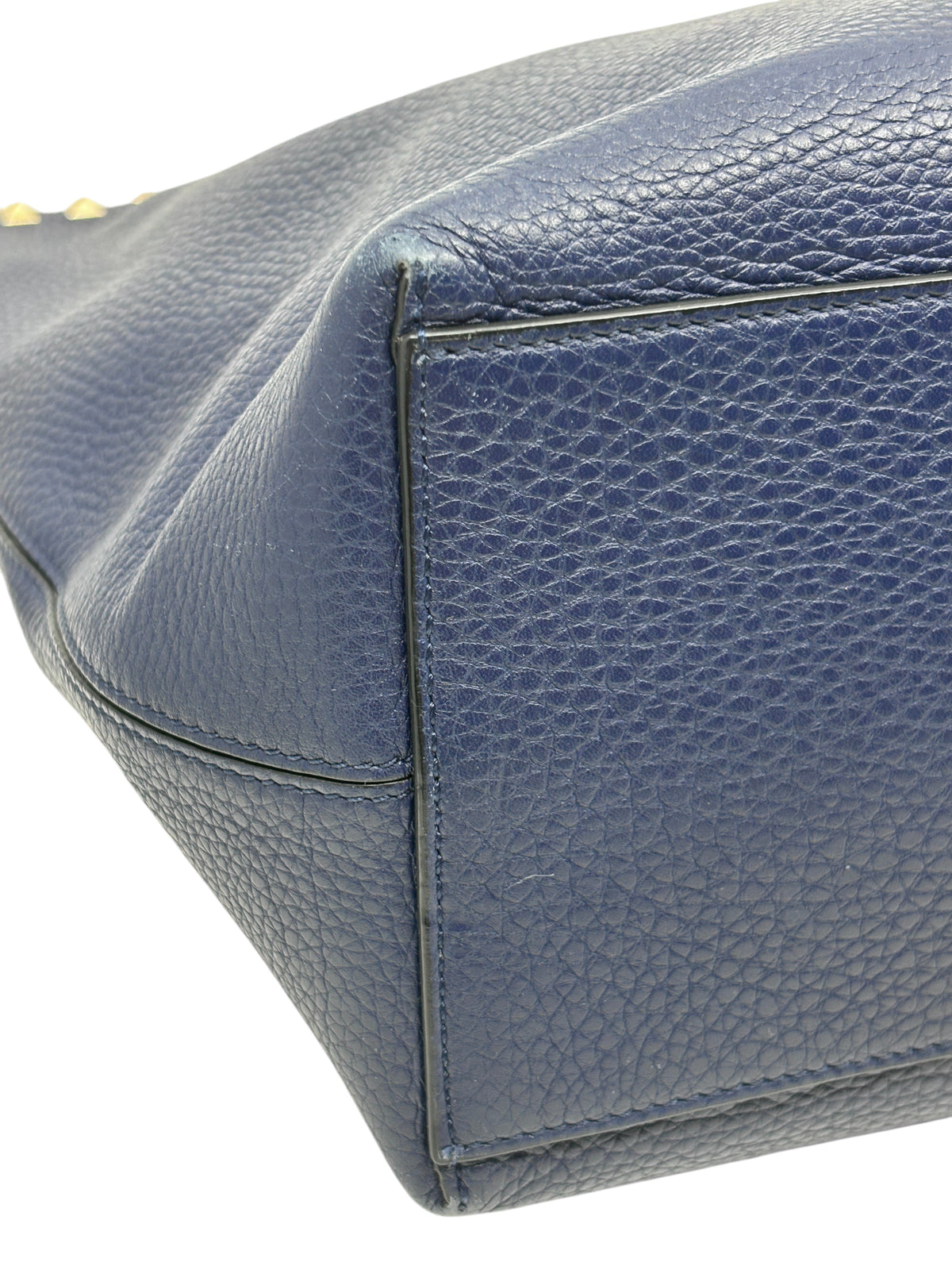 Close-up of the navy grained calfskin leather base and corner of a Posh Purse Co Valentino Rockstud shoulder tote.