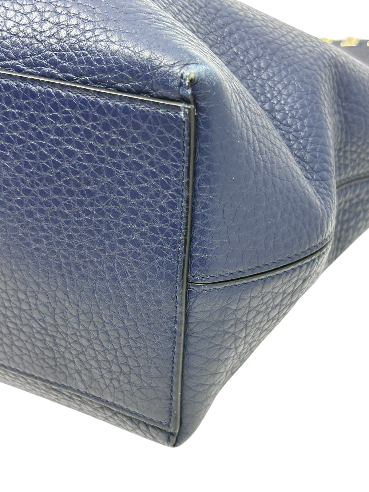 Close-up of the navy grained calfskin leather base and corner of a Posh Purse Co Valentino Rockstud tote bag.