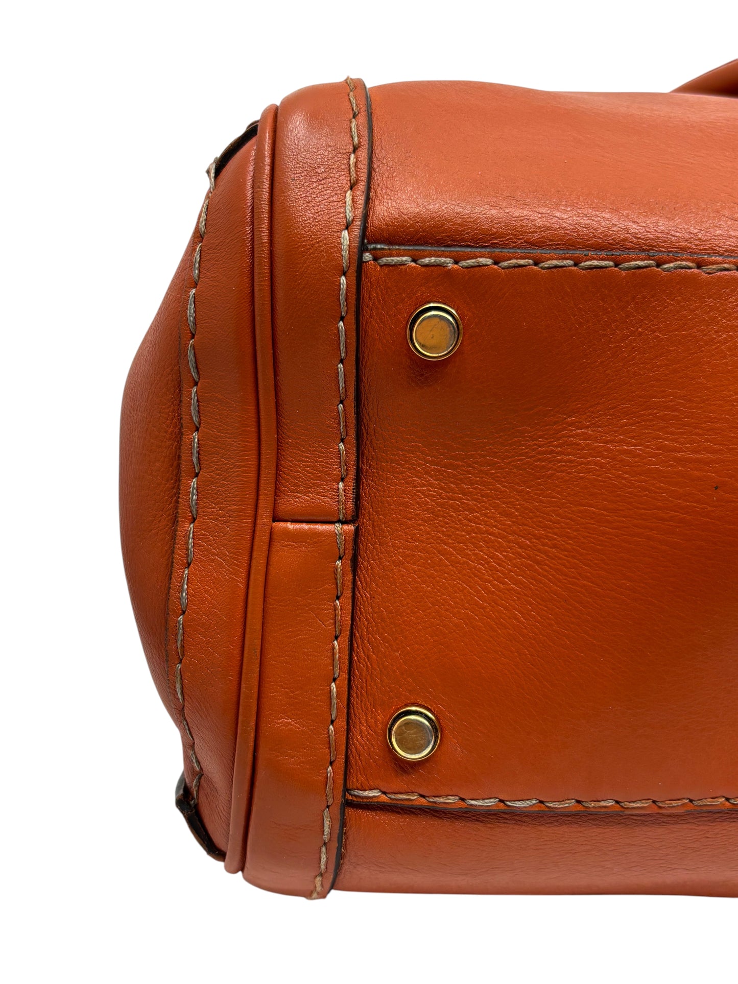 Close-up of the orange leather base and gold-tone protective feet of a Posh Purse Co. Gucci GG Running tote bag.