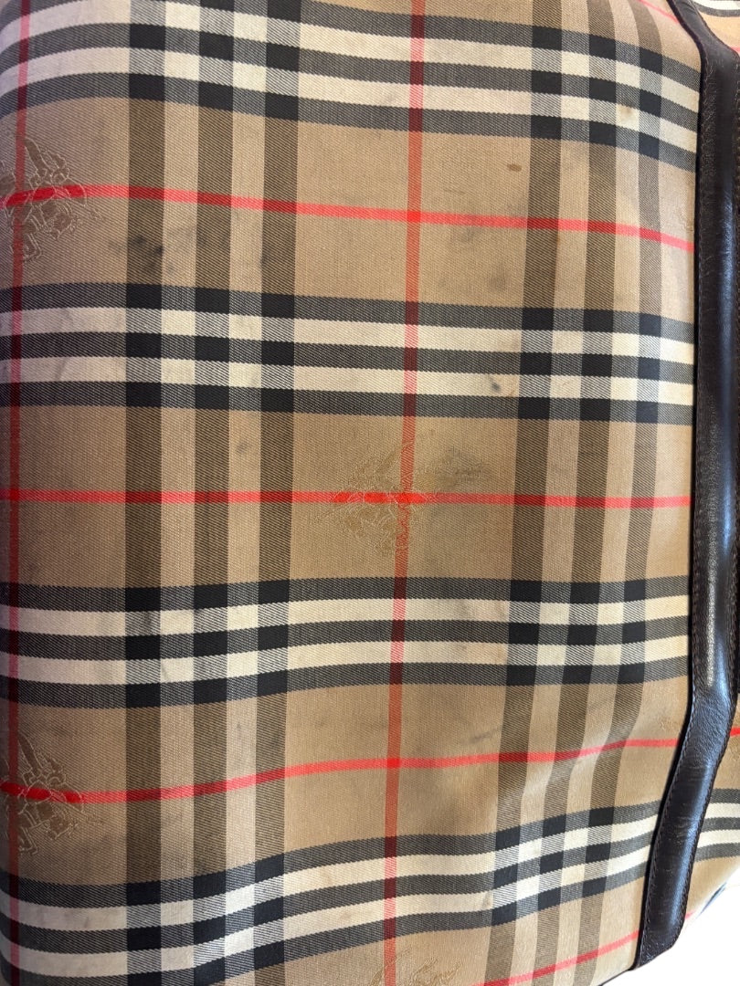 Posh Purse Co. Classic Plaid Weekend Duffle Bag in beige, black, red, and white with dark brown leather trim. Features iconic plaid pattern and embossed logo.