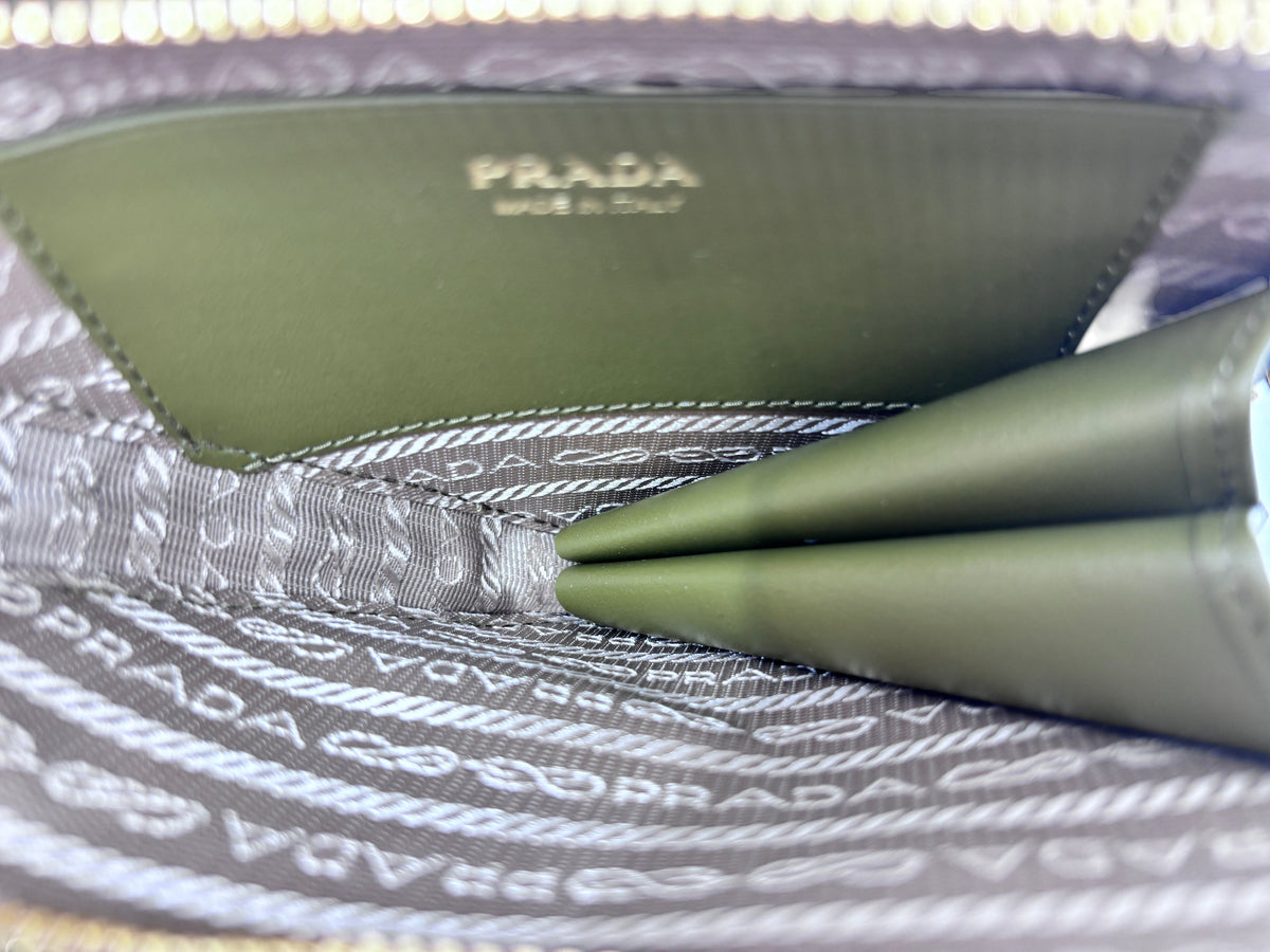 Interior of a Posh Purse Co green Prada mini triangle bag showing the Prada logo stamp and branded fabric lining