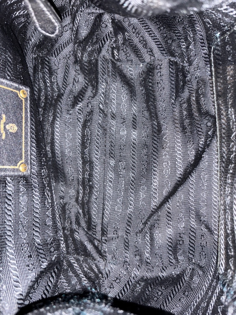 Posh Purse Co. black Prada nylon shoulder bag interior with repeating Prada logo lining and gold-tone logo plaque.