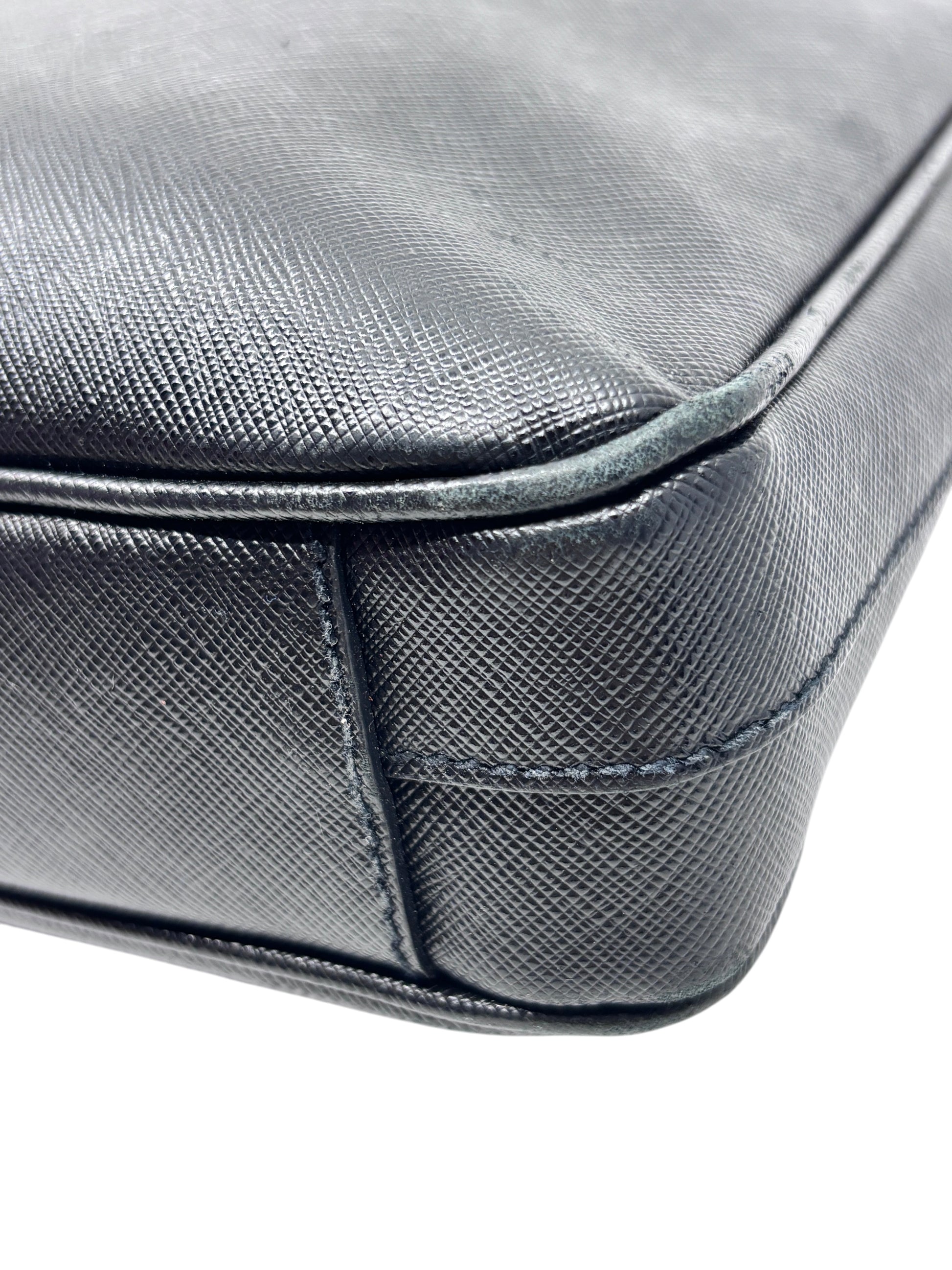 Close-up of Posh Purse Co black Saffiano leather Prada briefcase corner showing textured material and edge wear