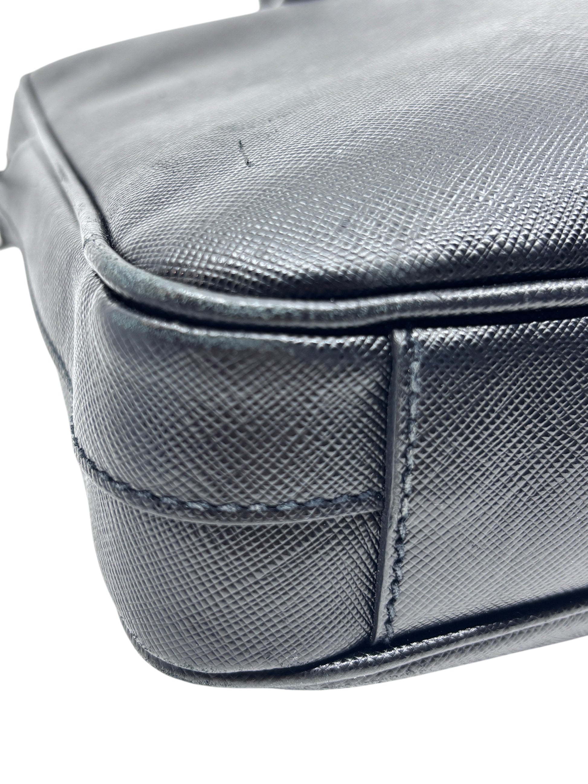 Close-up of the corner of a black Prada Saffiano leather briefcase from Posh Purse Co showing textured leather detail