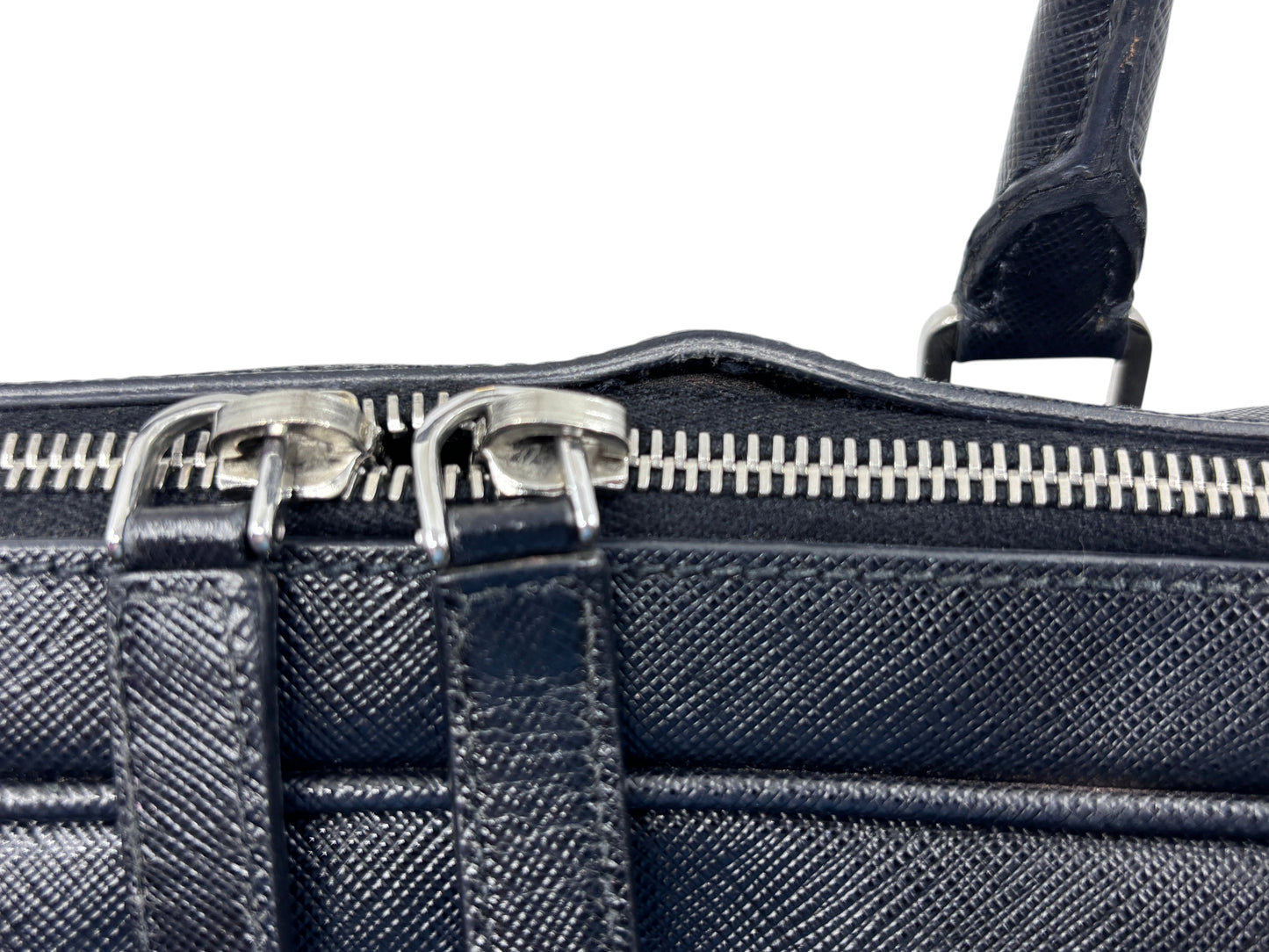 Posh Purse Co black Prada Saffiano leather briefcase showing silver metal zipper detail and textured leather finish