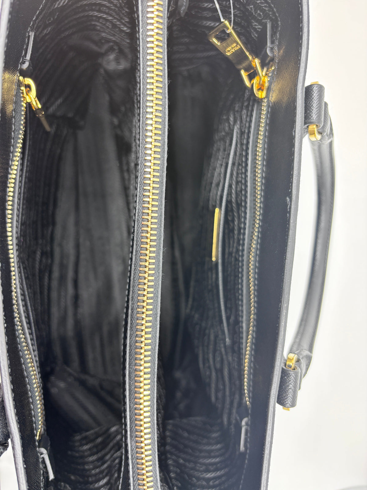 Interior view of a black Posh Purse Co Prada Saffiano leather tote featuring gold zippers and fabric lining