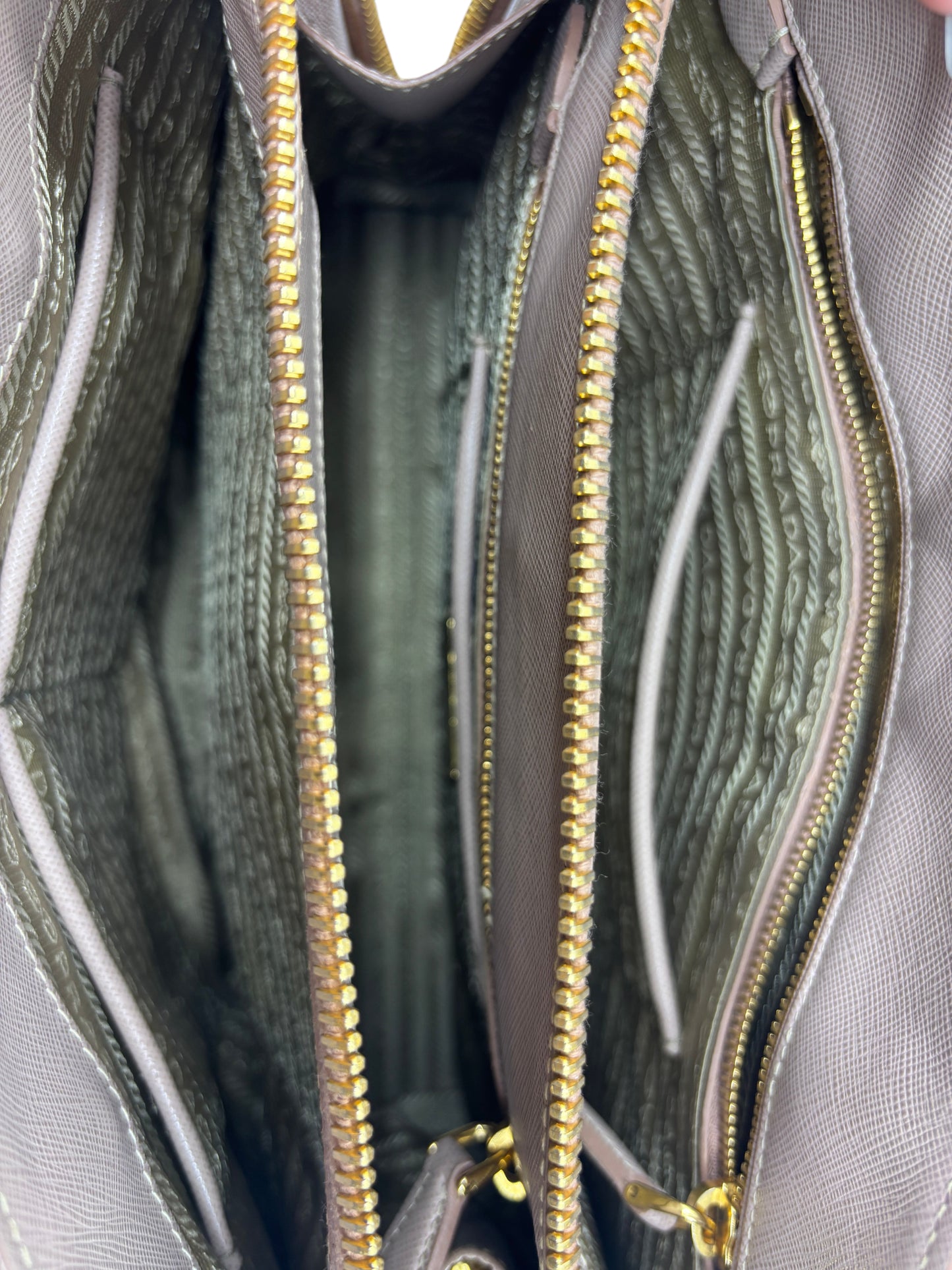Interior of a Posh Purse Co. beige Prada Saffiano leather tote featuring gold zippers and signature logo lining