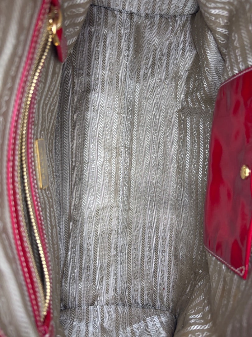 Interior of Posh Purse Co. Prada Vernice shoulder bag featuring beige logo-patterned lining and red patent trim.