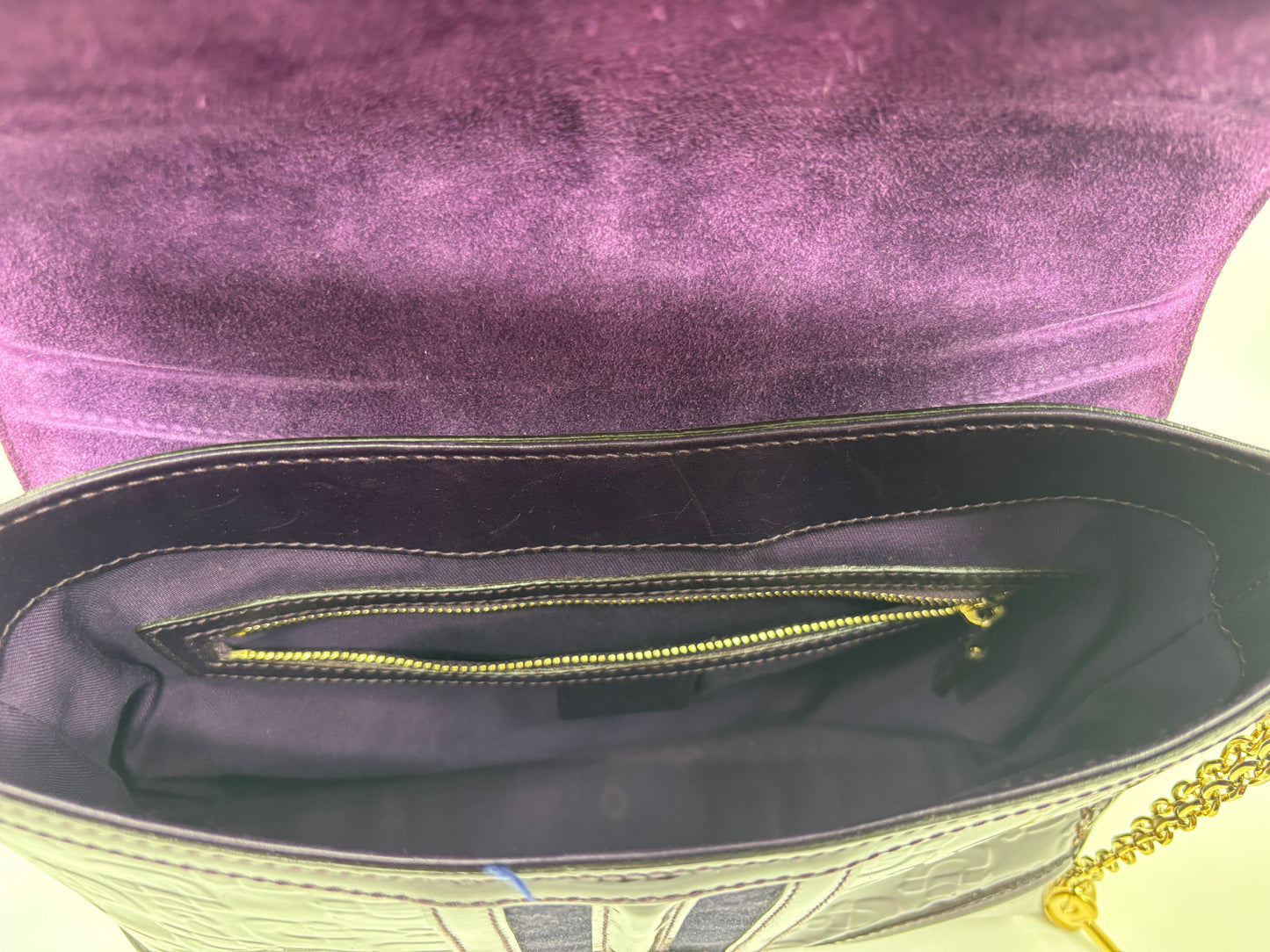 Interior of a Posh Purse Co. purple Gucci Horsebit Treasure bag featuring a zippered pocket and gold chain strap.