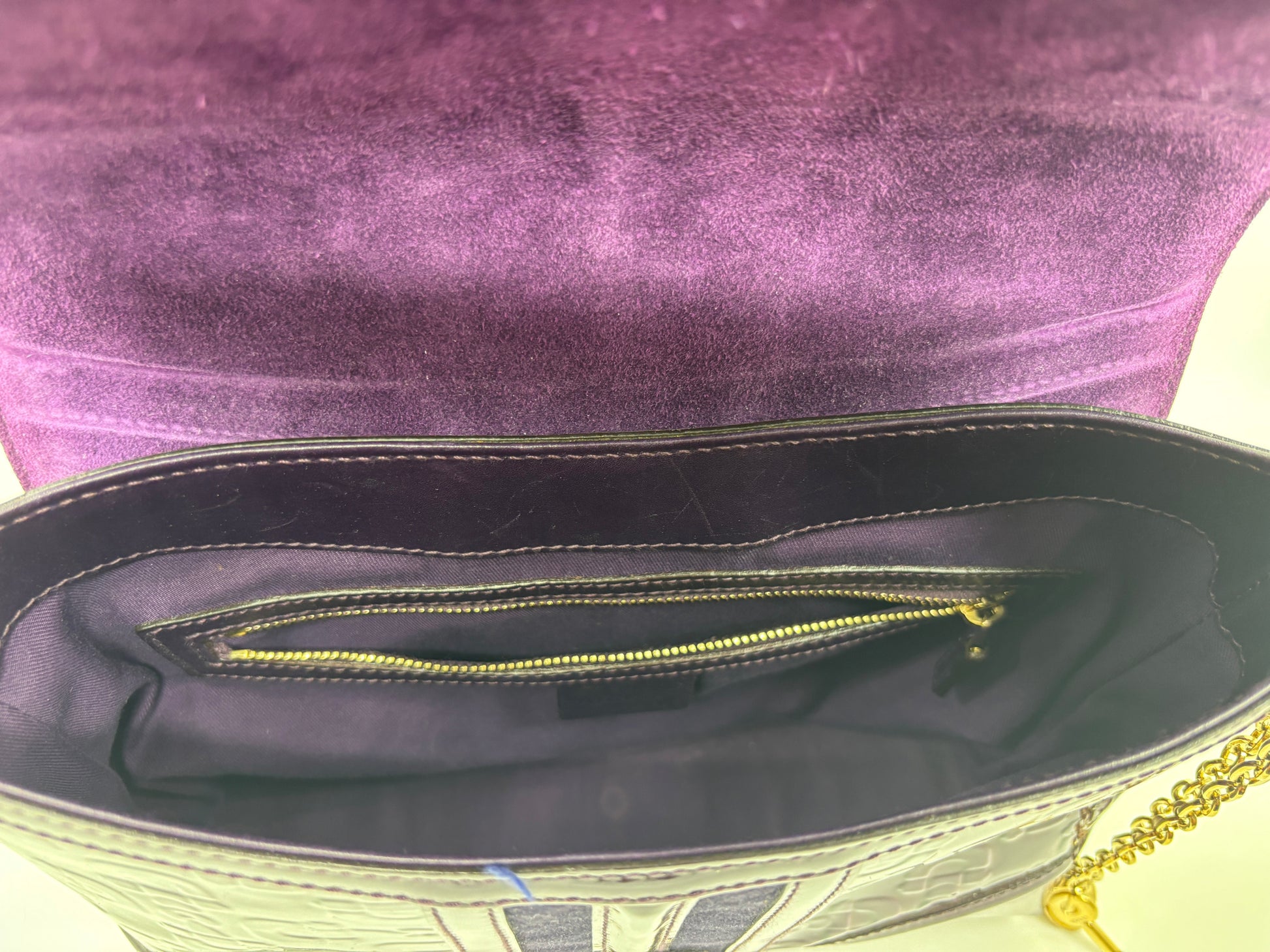 Interior of a Posh Purse Co. purple Gucci Horsebit Treasure bag featuring a zippered pocket and gold chain strap.