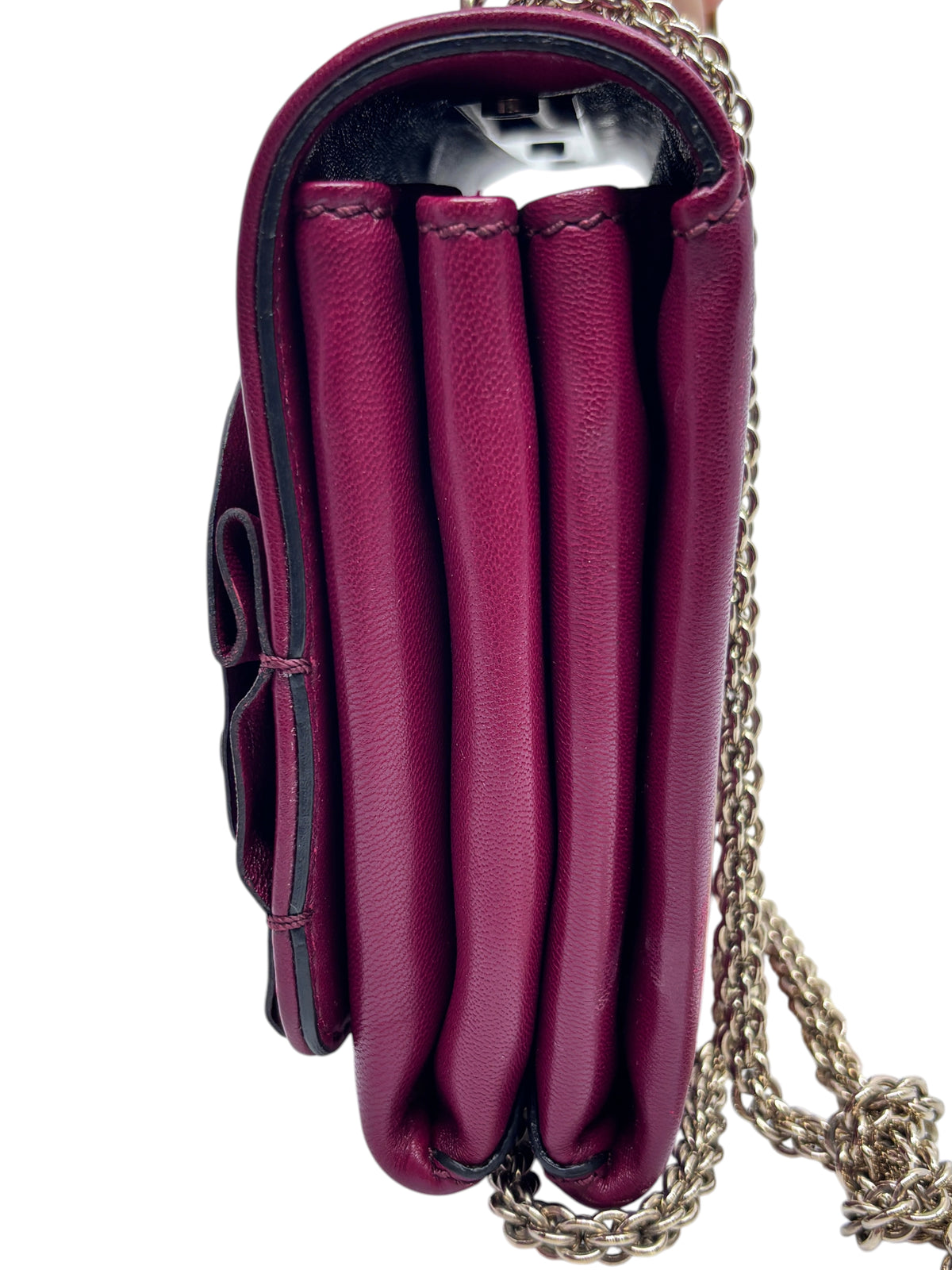 Side view of a Posh Purse Co. red Valentino flower crossbody bag with a gold chain strap and accordion compartments.