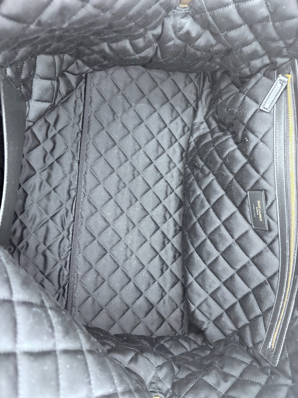 Interior of Posh Purse Co black Saint Laurent ES Giant travel bag featuring quilted fabric lining and gold zipper
