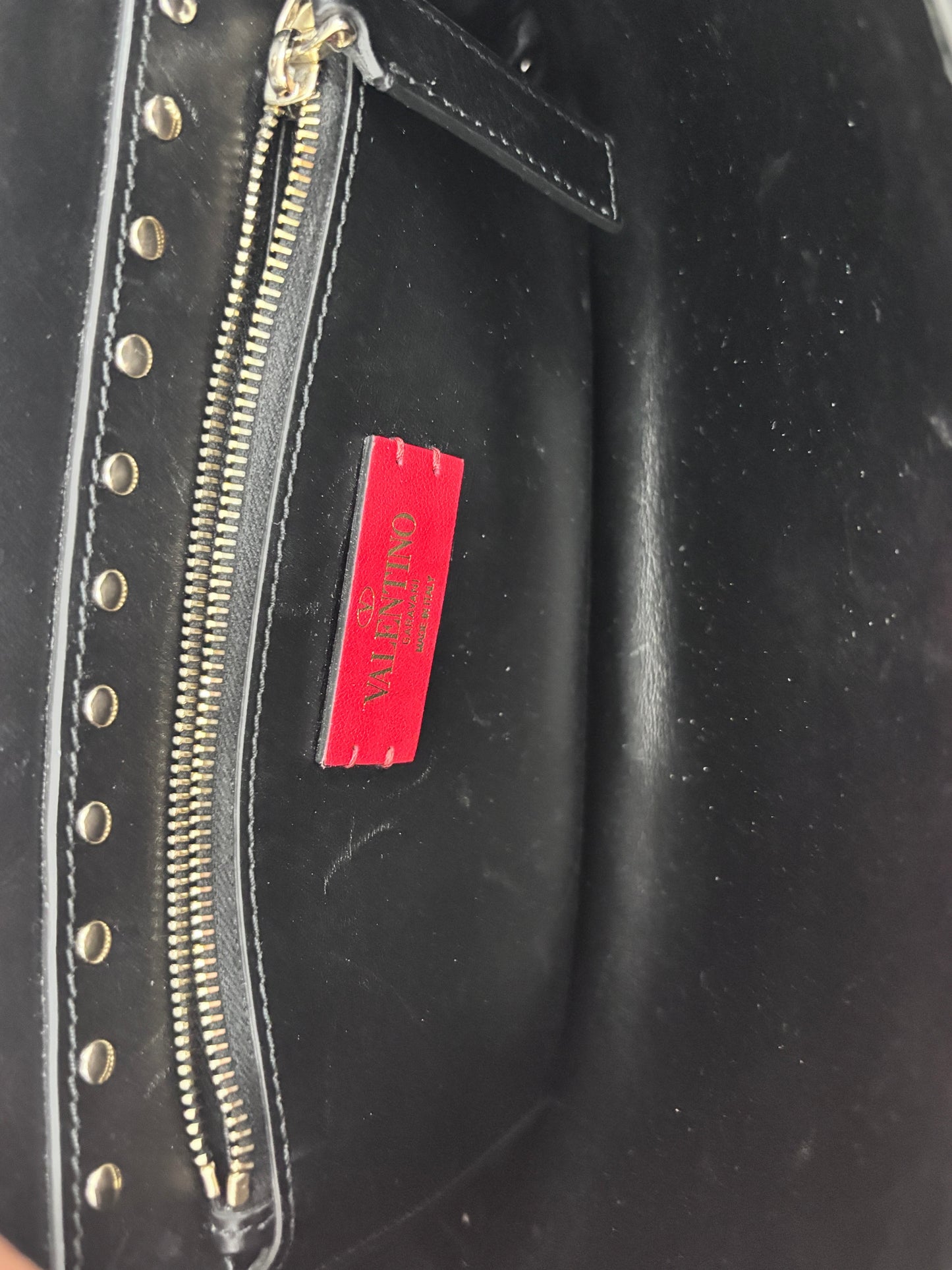 Interior of a black Posh Purse Co. Valentino Rockstud bag featuring a red brand label and gold-tone zipper hardware.