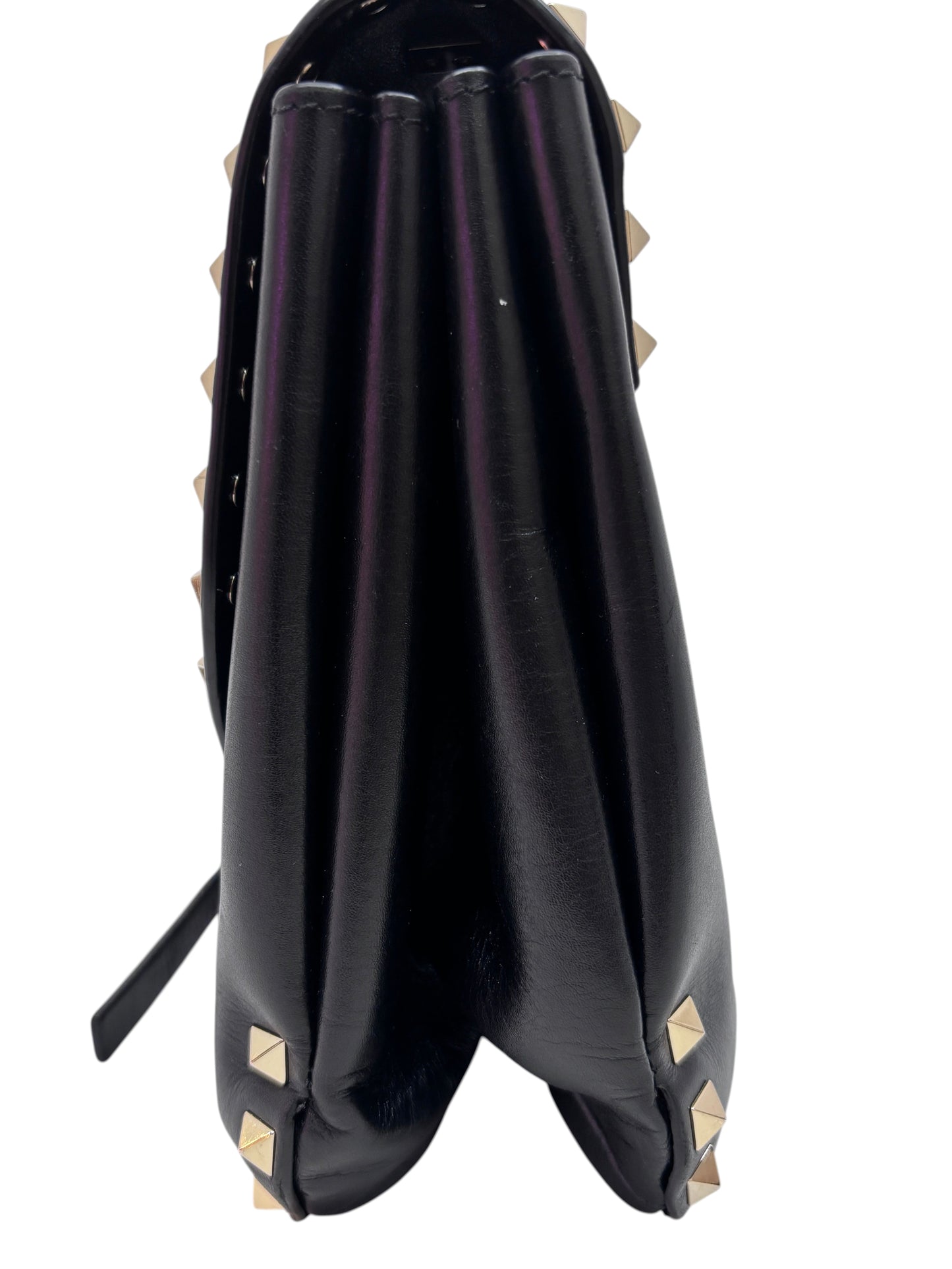 Side view of a black Posh Purse Co. Valentino Rockstud flap bag featuring gold pyramid studs and accordion gussets.