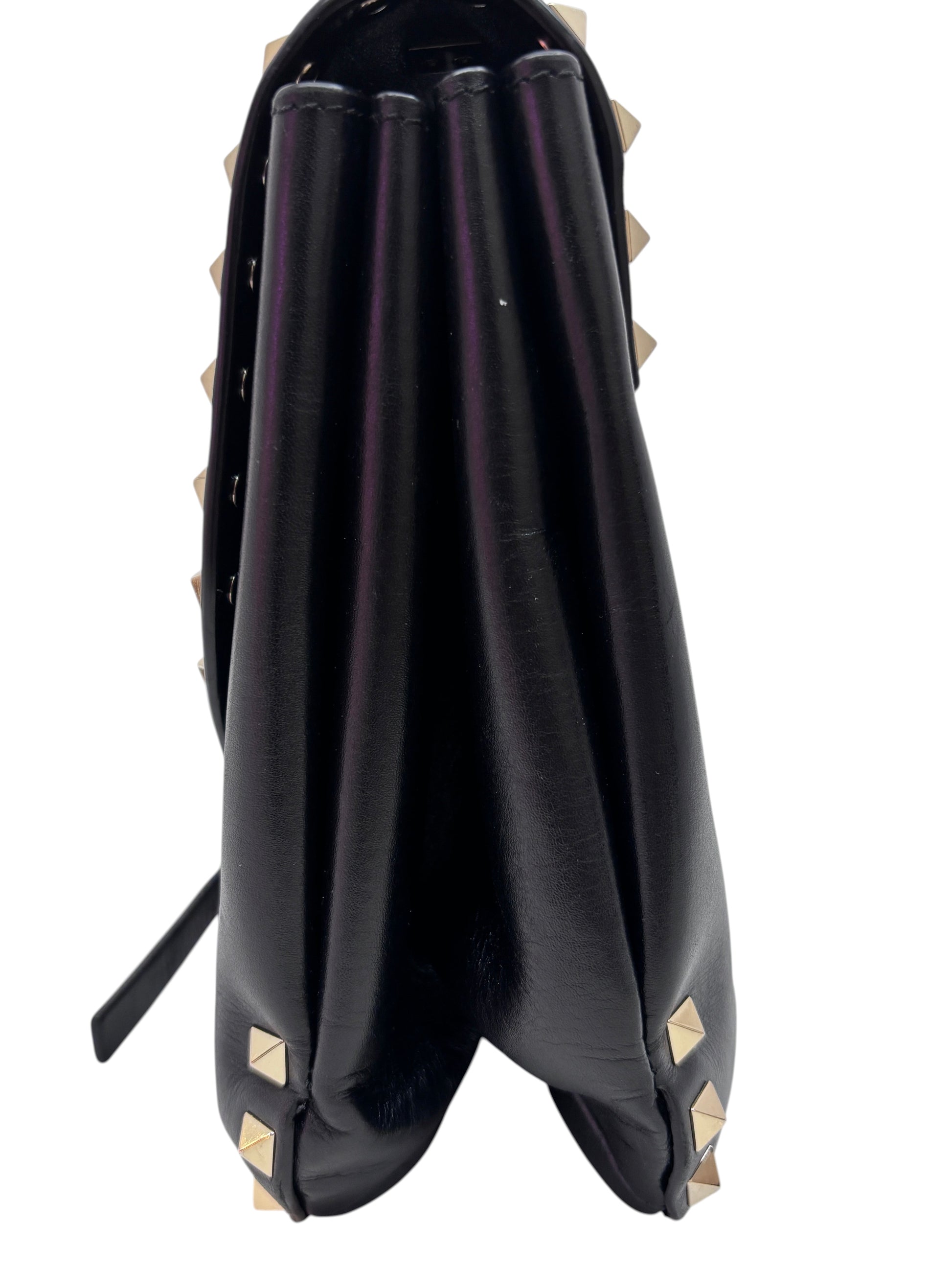 Side view of a black Posh Purse Co. Valentino Rockstud flap bag featuring gold pyramid studs and accordion gussets.