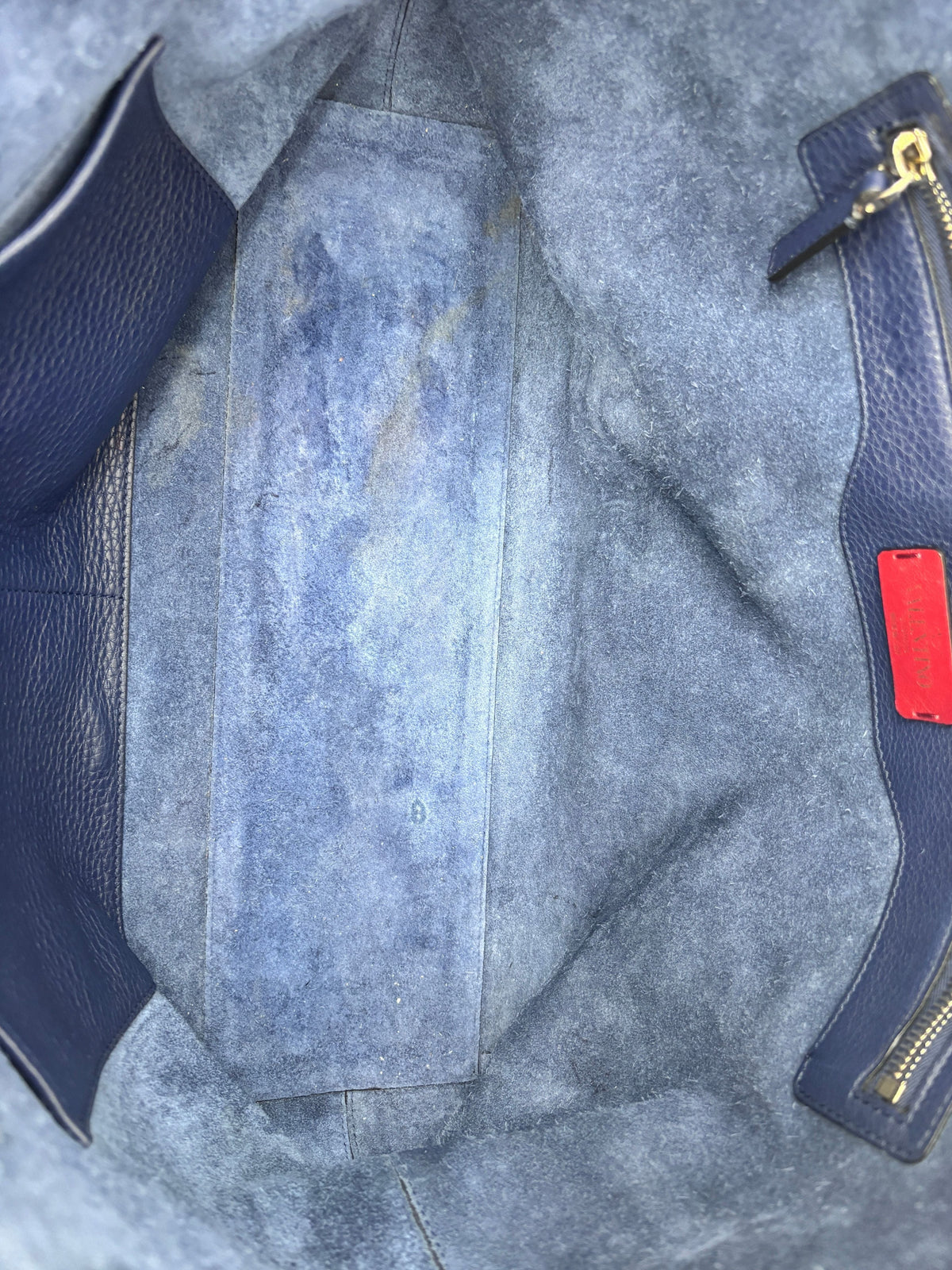Interior of a navy Posh Purse Co Valentino grained calfskin Rockstud tote showing suede lining and signs of wear