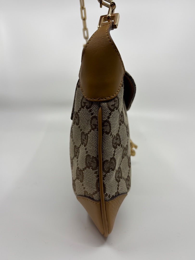 Side profile of a vintage Posh Purse Co. Gucci GG canvas shoulder bag with tan leather trim and gold chain strap.