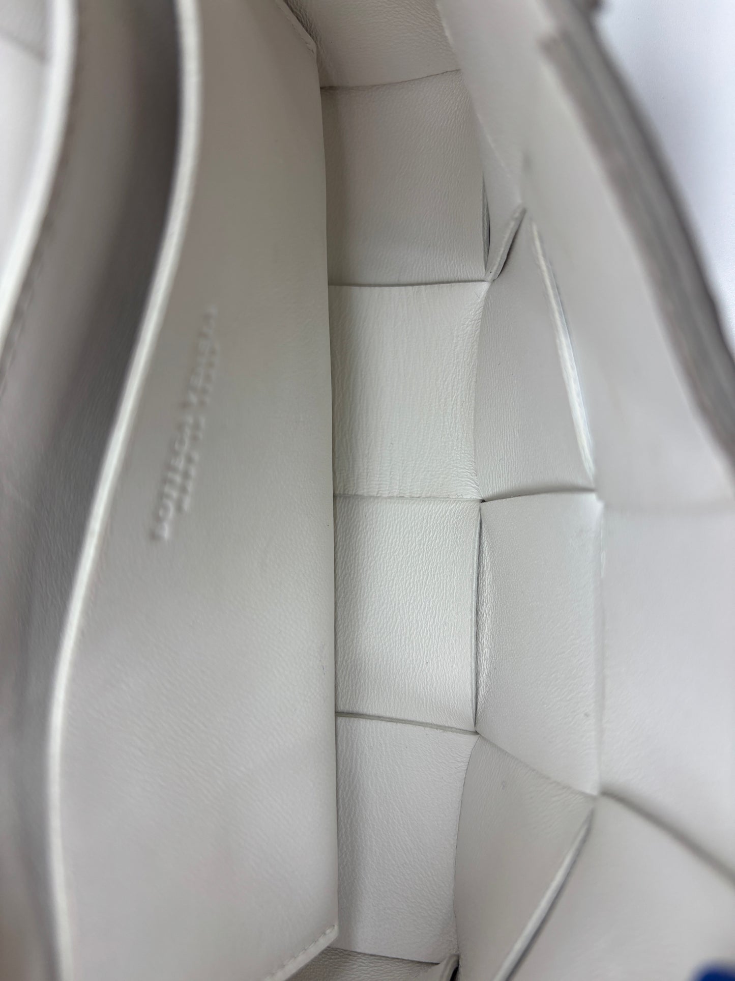 Interior of a white Bottega Veneta Cassette bag featuring signature Intrecciato woven leather by Posh Purse Co