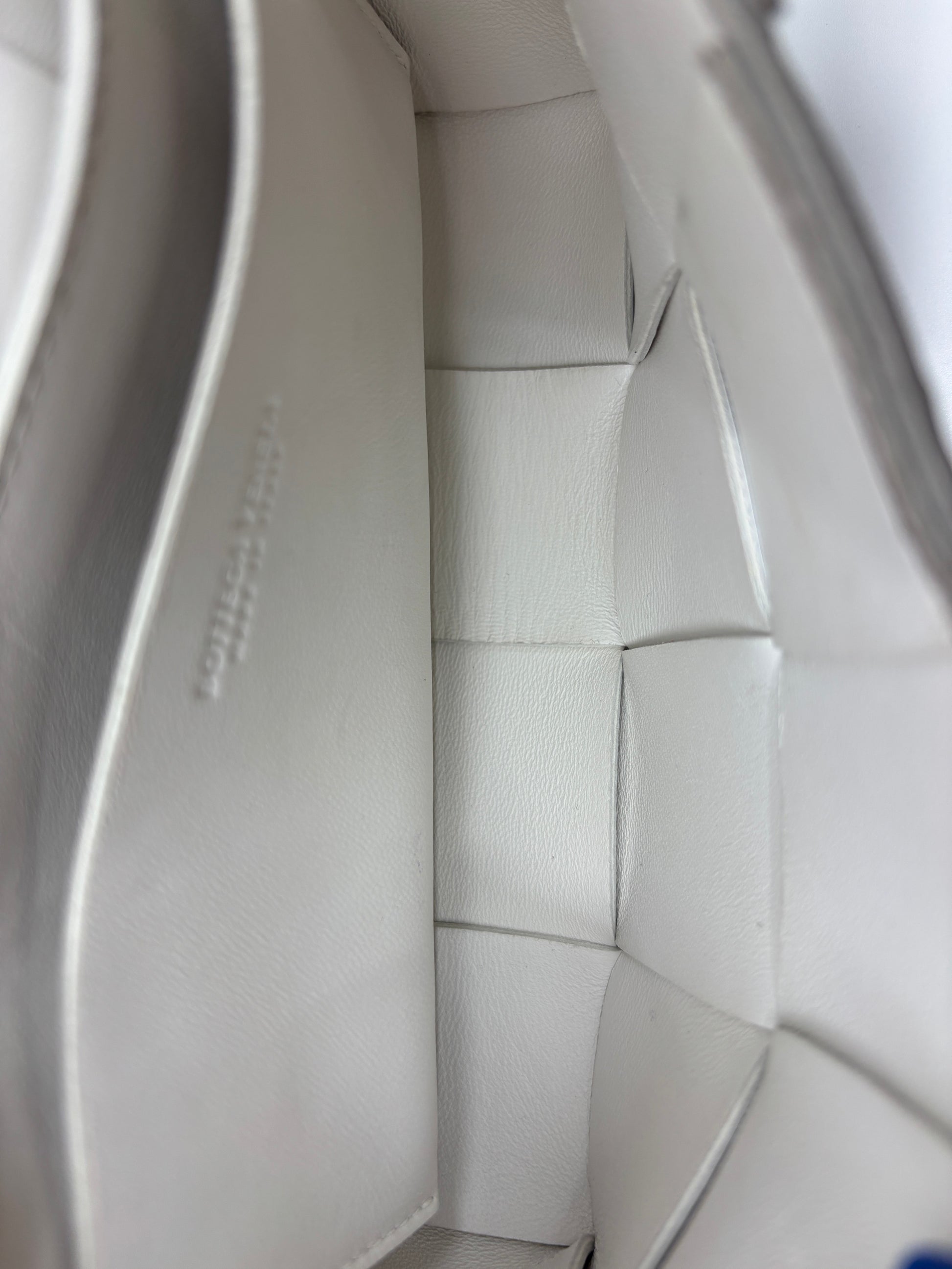 Interior of a white Bottega Veneta Cassette bag featuring signature Intrecciato woven leather by Posh Purse Co